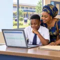 Nigerian parent and junior secondary school applicant checking an admission result on a laptop