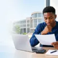 Nigerian university applicant reviewing an admissions score sheet beside a laptop and calculator