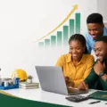 Nigerian technical examination candidates checking results on a laptop beside technical education materials